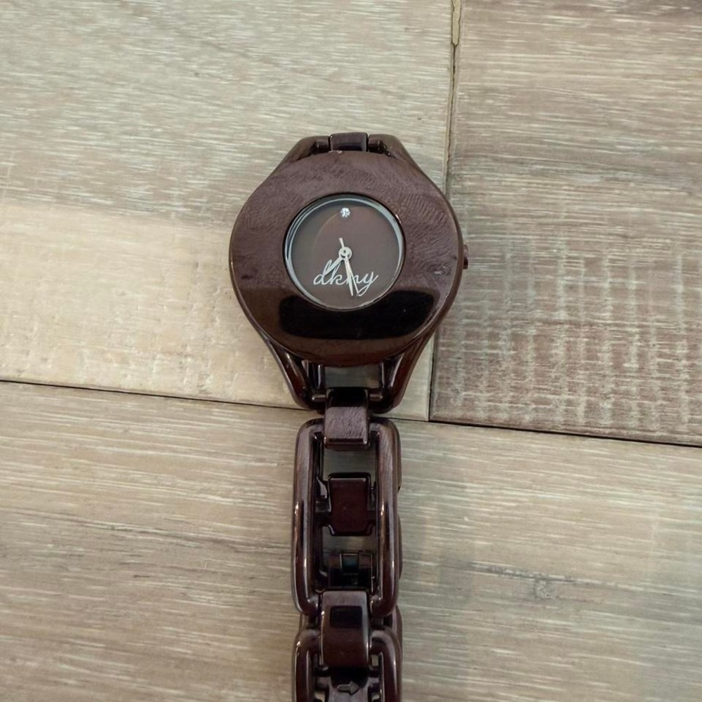 brown DKNY wristwatch featuring a distinct oval case and chain-link bracelet